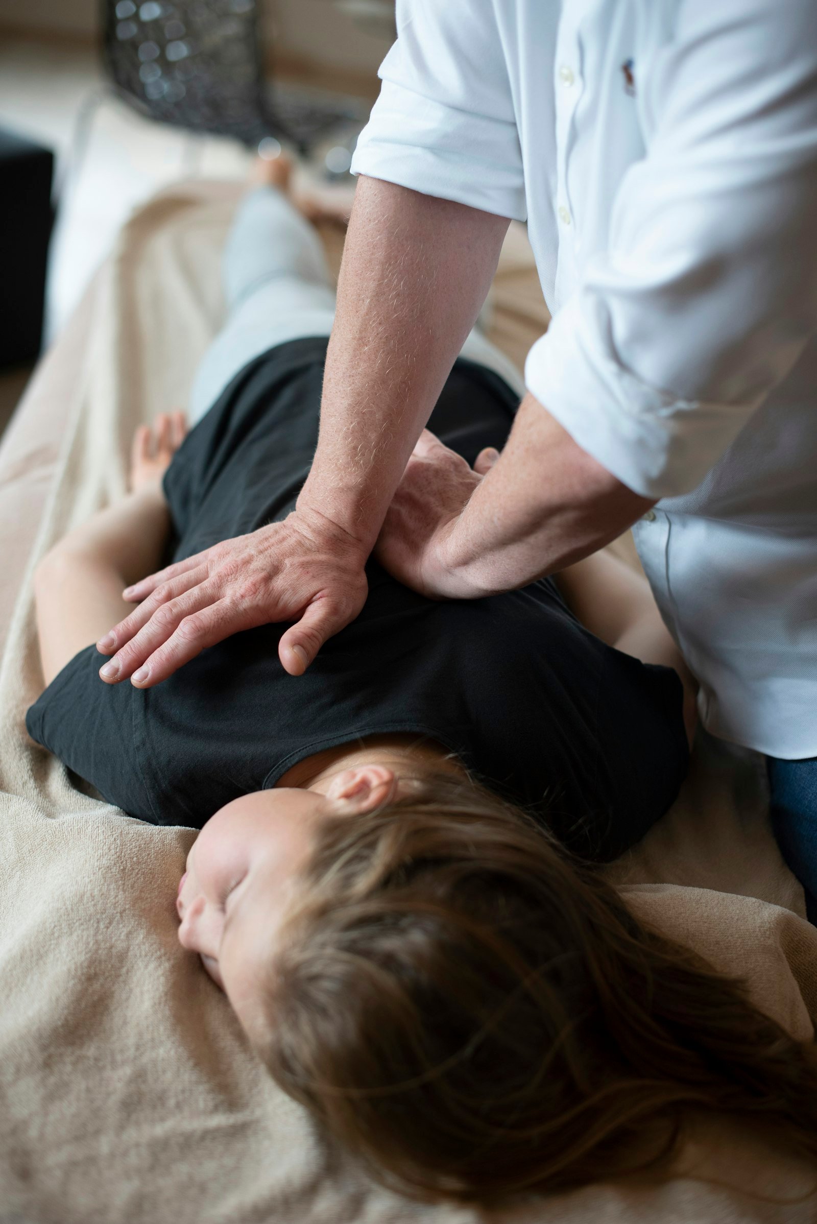 Osteopath's hands assessing a patient's upper back during a treatment