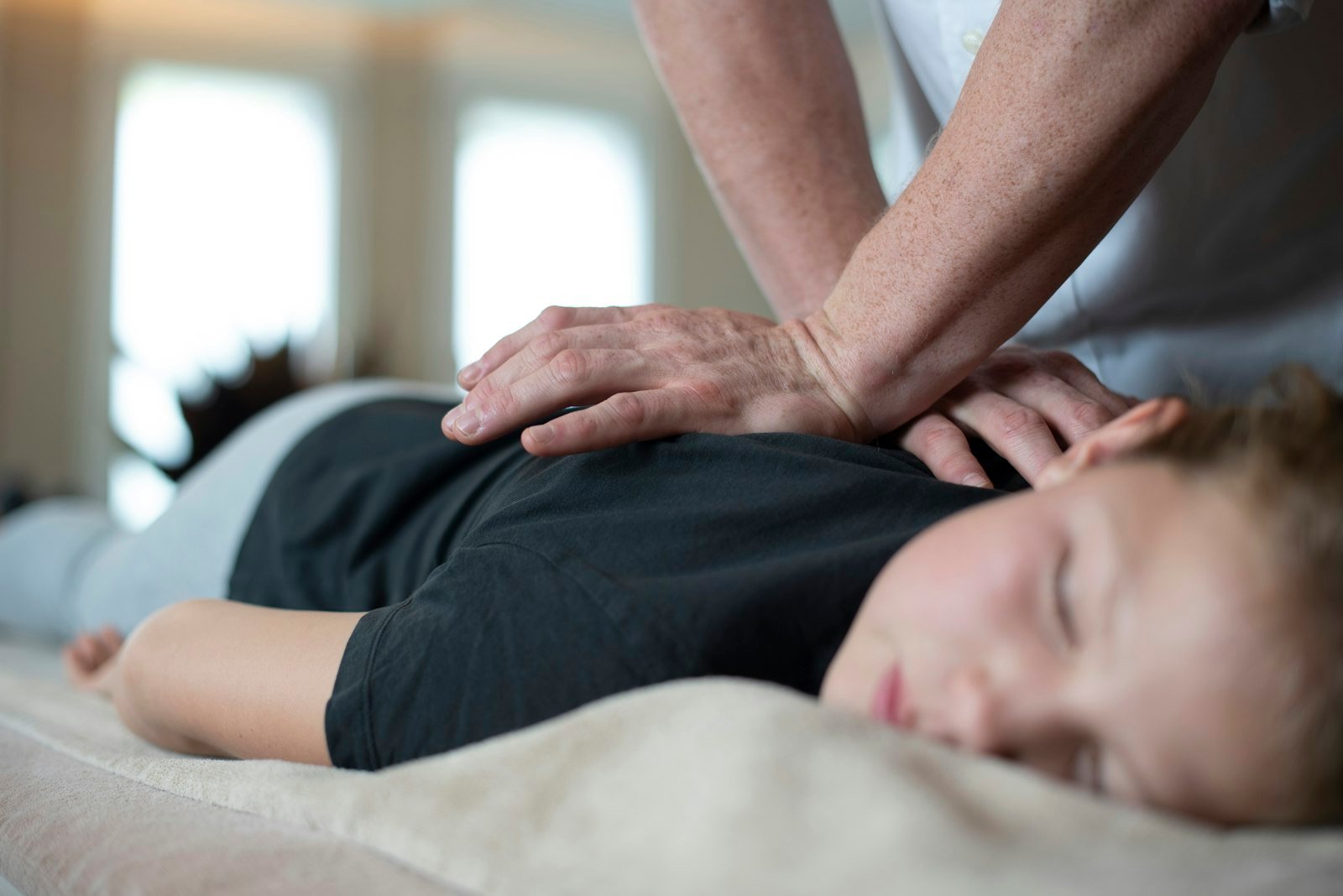 Osteopath's hands working on a patient's shoulder and upper back