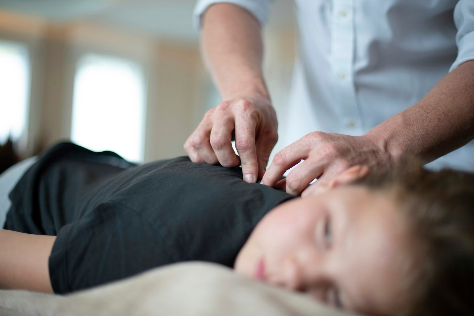 Gentle hands-on osteopathic treatment of the shoulder in a bright treatment room